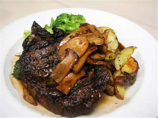 Grilled steak topped with sautéed mushrooms, served with roasted potatoes and steamed broccoli.