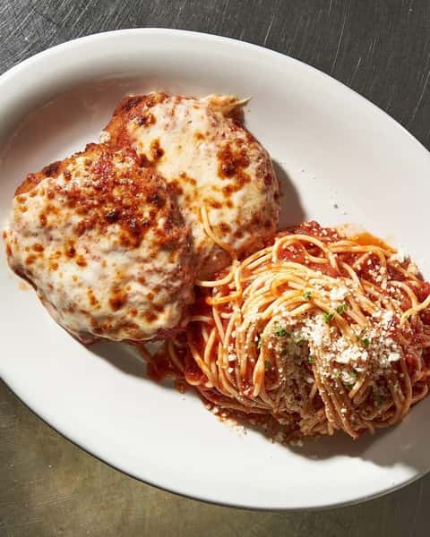 Classic Italian entrée featuring breaded chicken parmesan topped with melted mozzarella and marinara, served alongside spaghetti tossed in tomato sauce and sprinkled with grated cheese.