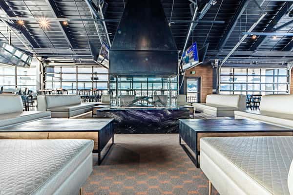 Contemporary restaurant lounge with fireplace centerpiece, plush booth seating, floor-to-ceiling windows, and a stylish social atmosphere.