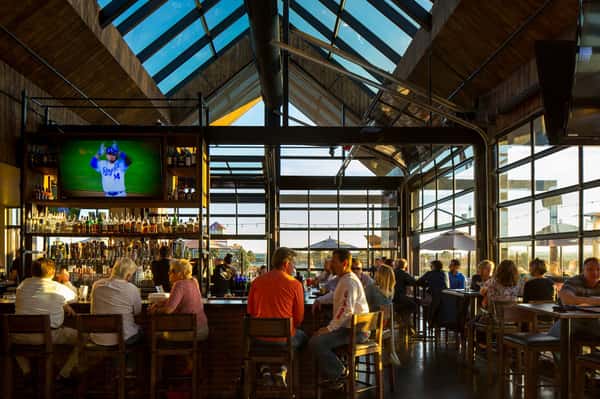 Guests enjoying drinks and dining at the ViewHouse bar beneath vaulted ceilings, floor-to-ceiling windows, and panoramic rooftop views.