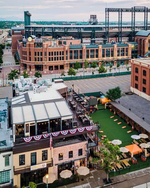 Aerial view of ViewHouse featuring rooftop dining, outdoor event lawn, patio seating, and entertainment spaces adjacent to a downtown sports district.