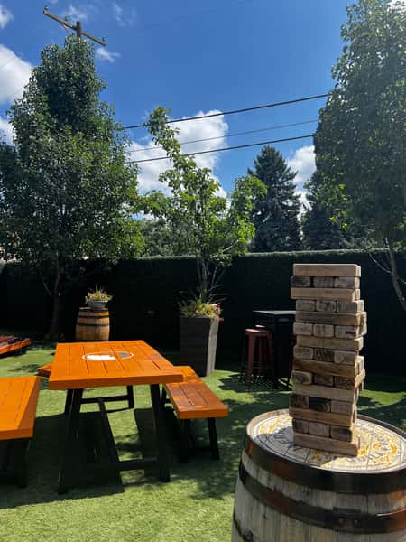 Outdoor lawn game area featuring giant Jenga, picnic-style seating, and landscaped gathering space for social events and casual entertainment.