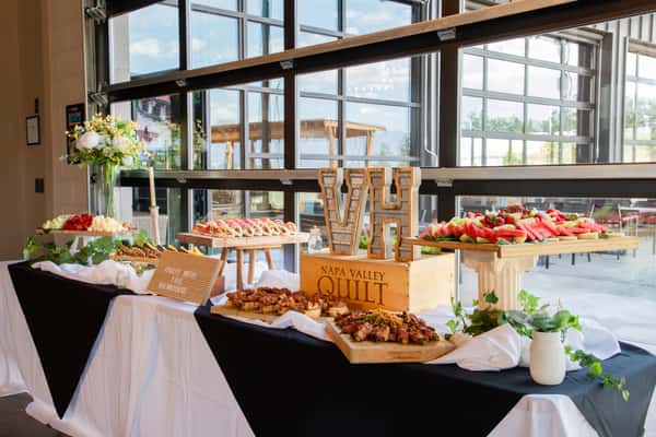 Elegant catering buffet display with assorted appetizers, fresh fruit platters, and event dining setup inside a modern restaurant venue.