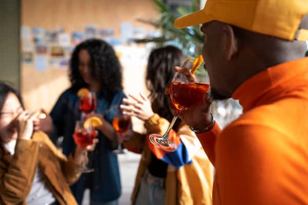 Friends enjoying orange cocktails with citrus garnish at trendy bar, casual social gathering with craft drinks