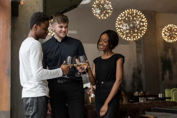 Group of friends toasting white wine in stylish restaurant lounge with warm lighting and upscale dining ambiance