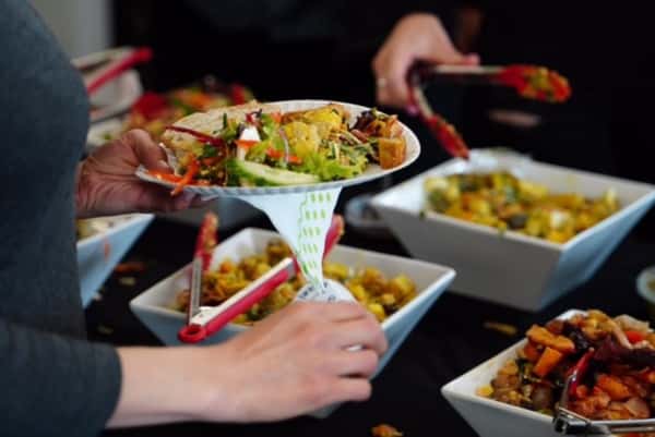 Guest serving themselves fresh salad and hot buffet dishes from a self-serve catering station with bowls of mixed vegetables and prepared entrées—casual restaurant buffet dining experience.
