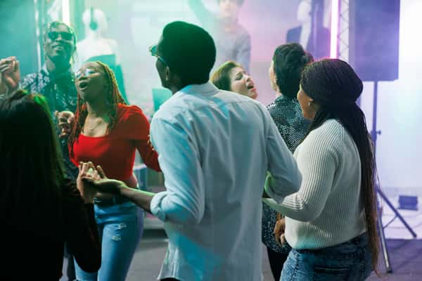 Friends dancing in vibrant nightclub with colorful lighting and energetic party atmosphere, lively social nightlife scene