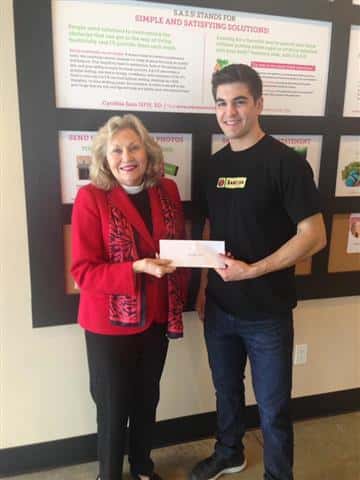 male and female posing for picture holding a check
