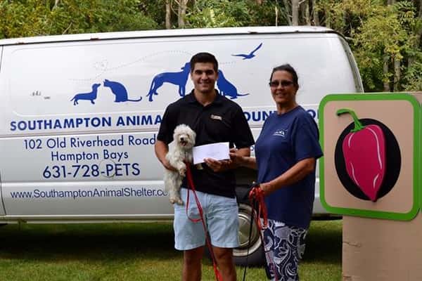 two men posing for picture holding a check