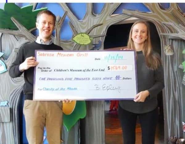 male and female posing for picture holding a check