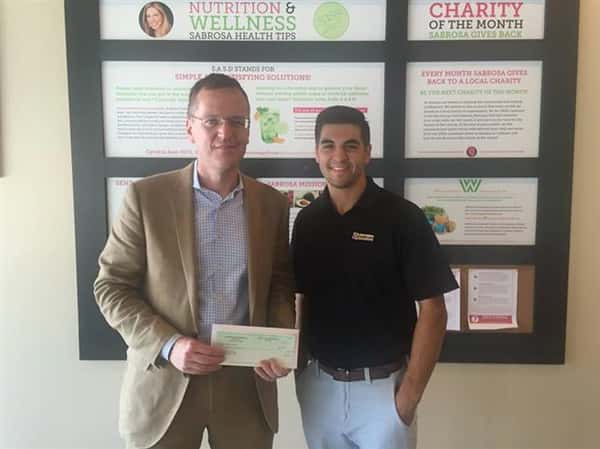 two men posing for picture holding a check