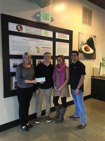 four people posing for picture holding a check
