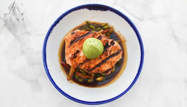 Sriracha dusted grilled salmon over ponzu roasted vegetables and a sticky rice cake, (mango, ginger, jalapeño, bell pepper, onion & sushi rice), finished with an avocado purée