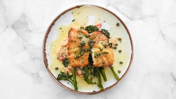 Seared black grouper served over a garlic, shallot, and blistered tomato, broccolini, topped with a lemon butter caper sauce