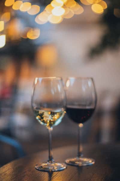 Red and white wine glasses on a table with warm ambient lighting and elegant evening dining atmosphere