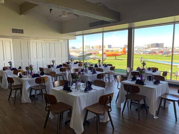 Private event dining room with runway views, modern table settings, and aviation-themed scenery for upscale receptions and corporate events