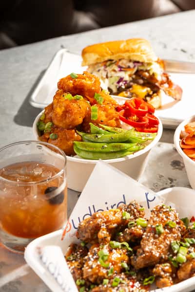 Crispy cauliflower bites and glazed chicken wings served with sliders, avocado, and craft cocktails at a trendy comfort food restaurant