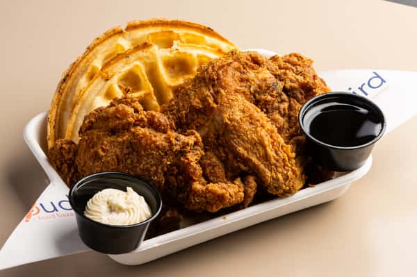 Crispy fried chicken and waffles served with syrup and whipped butter at a Southern-inspired comfort food restaurant
