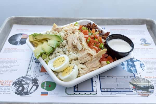 Grilled chicken Cobb salad with avocado, blue cheese, bacon, tomatoes, and hard-boiled eggs served in a modern restaurant bowl