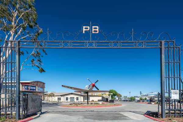 Entrance gate to an aviation-themed restaurant and event venue featuring vintage aircraft displays and industrial outdoor architecture