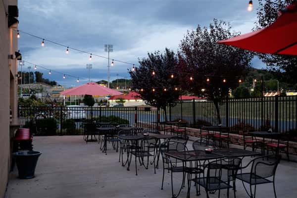 Restaurant patio vie with tables and red umbrellas decorated with string lights
