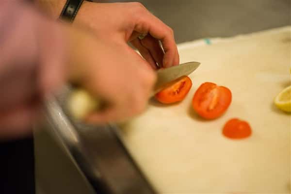 Close up photo of someone cutting up a a tomato to wedges