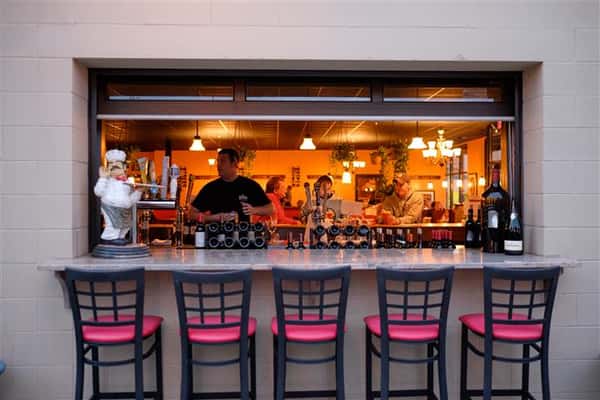 Photo of the outside bar with the stools and the bar tender behind it