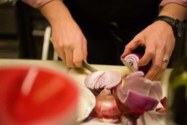 Close up photo of someone cutting up red onions