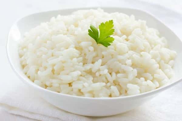 Fluffy white steamed rice served in a minimalist white bowl, garnished with a fresh parsley leaf – a simple and classic side dish in Asian and Hawaiian cuisine.