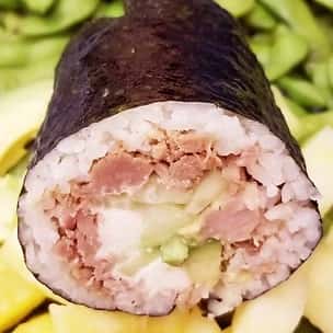 Close-up of a sushi burrito roll filled with raw tuna, avocado, cucumber, and sushi rice, wrapped in nori – a fusion of Japanese sushi and portable street food style.