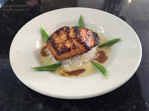 seared salmon on top of white rice with a creamy broth on the bottom