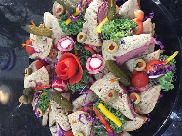 catering platter with cold cuts sandwiches, and decorated veggies