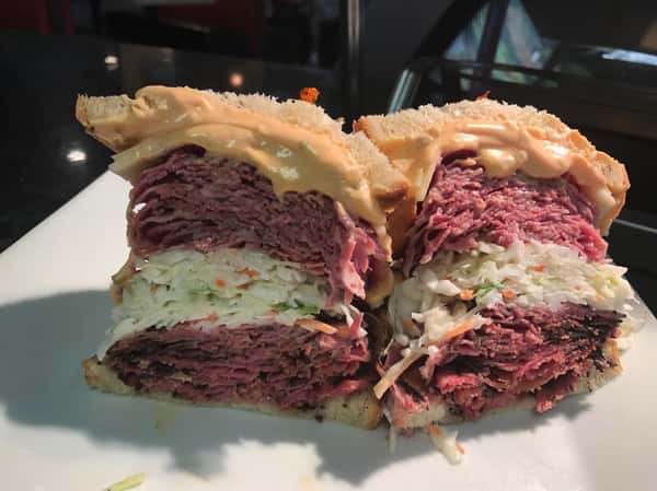 Ruben sandwich with coleslaw in the middle and thousand island dressing between rye bread