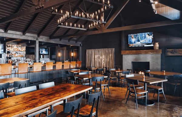 Whiskey 'N Rye bar area with TV's and dark wood tables and chairs and soft indoor lighting by a fireplace