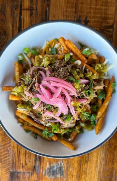 Mixed dish containingmeat, fries, sauces, and a garnish of greens