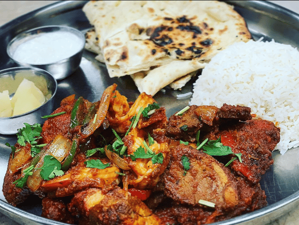 Indian food with meat, rice, naan, dip and fruit