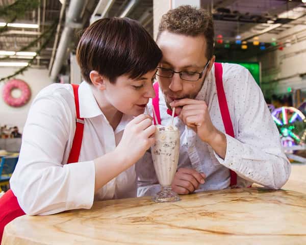 two people drinking out of a milkshake