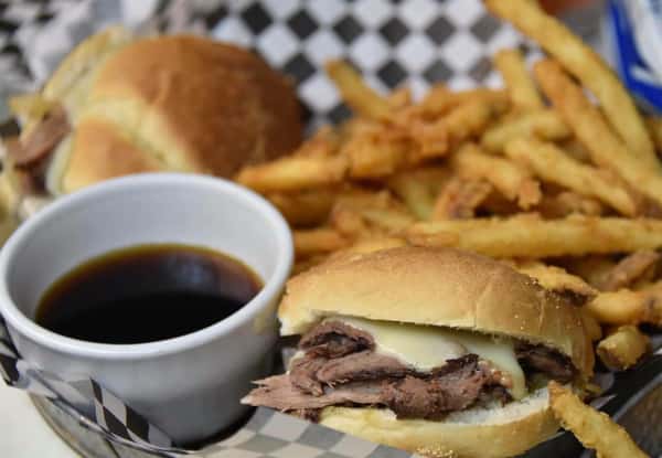 brisket with cheese sandwich, fries and a dipping sauce on the side