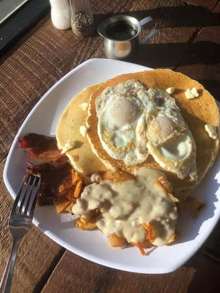 pancakes with eggs, bacon, and homefries with gravy on top