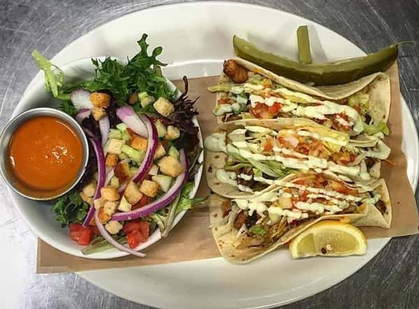 Fish tacos. Blackened whitefish, house made kimchi, cole slaw, tropical salsa, wasabi aioli with side salad with croutons, tomatoes, onions
