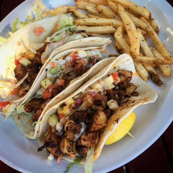 Fish tacos. blackened fish, kimchi, cole slaw, tropical salad, shredded cheese shredded lettuce & wasabi aioli with fries