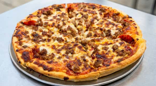 Meat pizza with sausage and pepperoni on a metal tray, sliced into eight pieces.