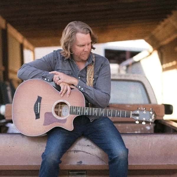 Singer sitting in truck bed with guitar