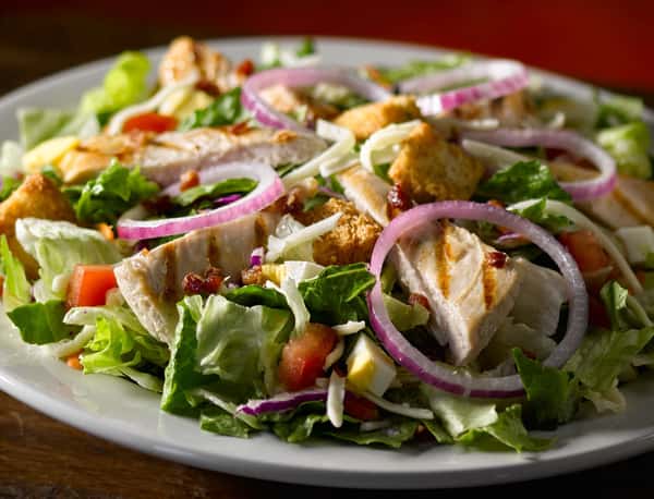 garden salad topped with chicken slices, onions, tomatoes and croutons