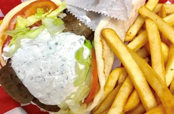 gyro topped with tzatziki sauce, tomatos, lettuce and a side of fries