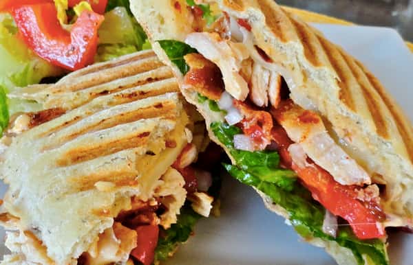 chicken panini topped with lettuce, tomatos and bacon