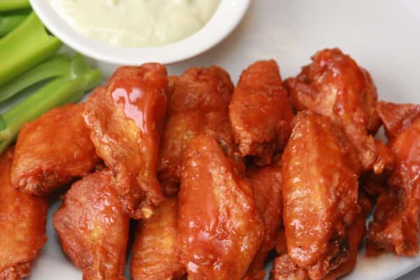 buffalo hot wings covered in sauce with a side of bleu cheese