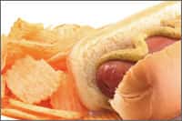 Hot dog with mustard and a side of chips