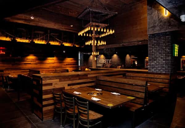 Thirsty Cow Korean BBQ interior with wooden booth seating, grill tables, and a chandelier centerpiece under warm lighting.