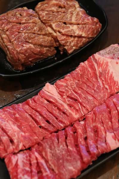 Plates of raw beef prepared for Korean BBQ, including marinated cuts and thinly sliced short ribs ready for grilling.